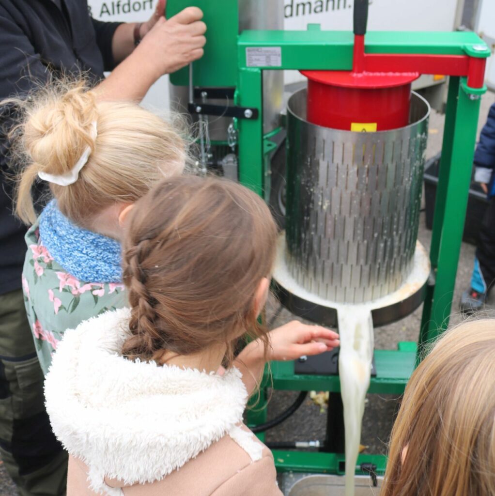 Die Kinder bestaunen den Saft, der unten herausläuft.