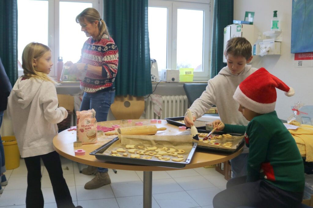 Drei Kinder in der Weihnachtsbäckerei.