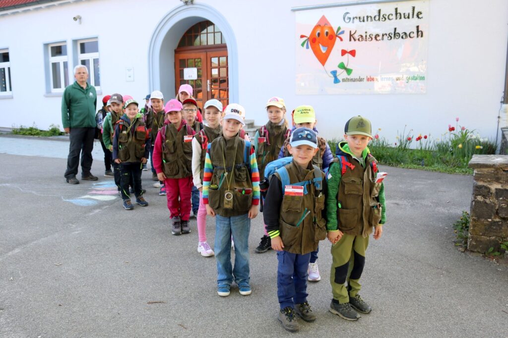 Mit Entdeckerwesten warten die Kinder vor der Schule.