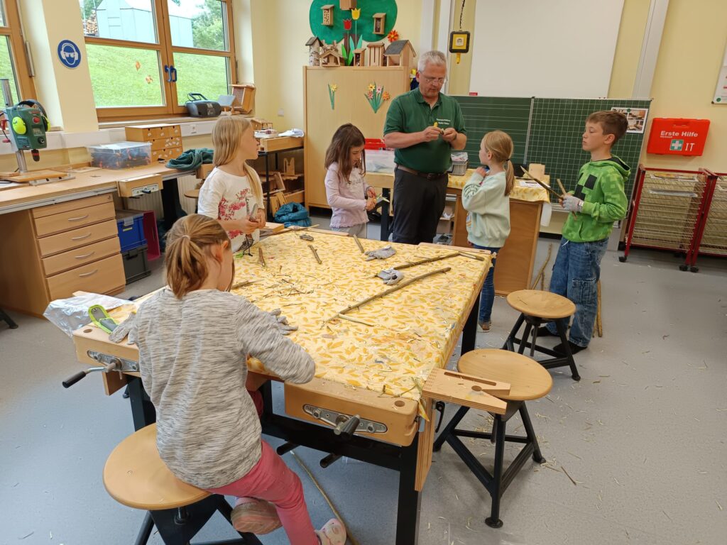 Blick in den Werkraum mit Walter Hieber und Kindern beim Schnitzen
