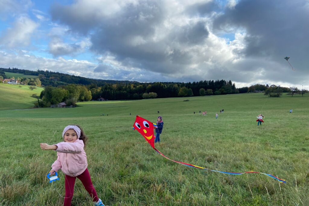 Kinder lassen am Hang bunte Drachen steigen.