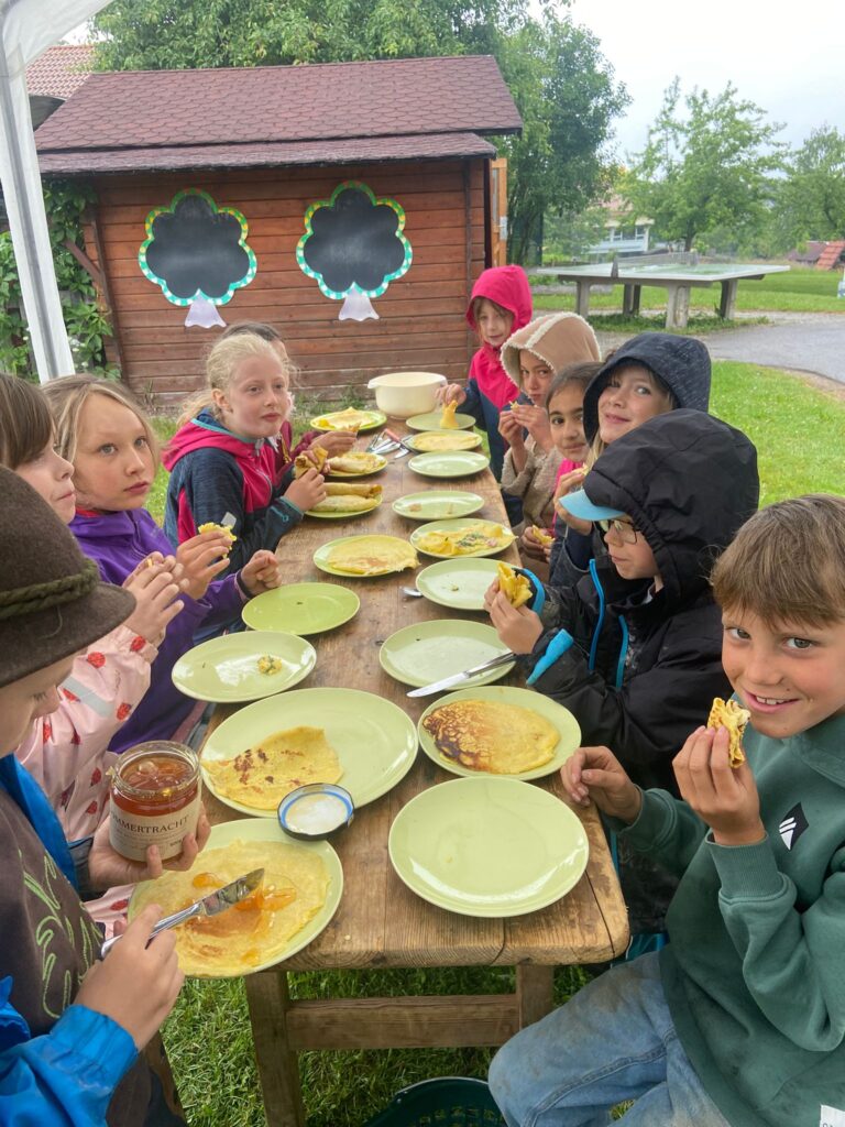 Viele Kinder lassen sich am Tisch die Pfannkuchen schmecken