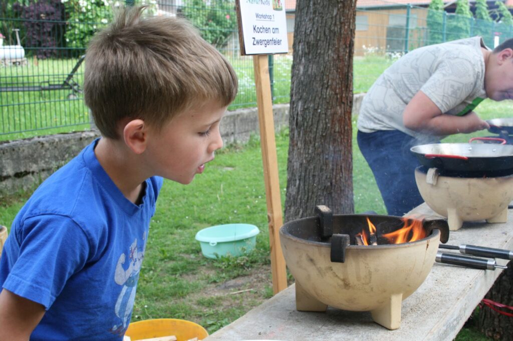 Ein Junge kontrolliert sein Feuer im Zwergenfeuerpot