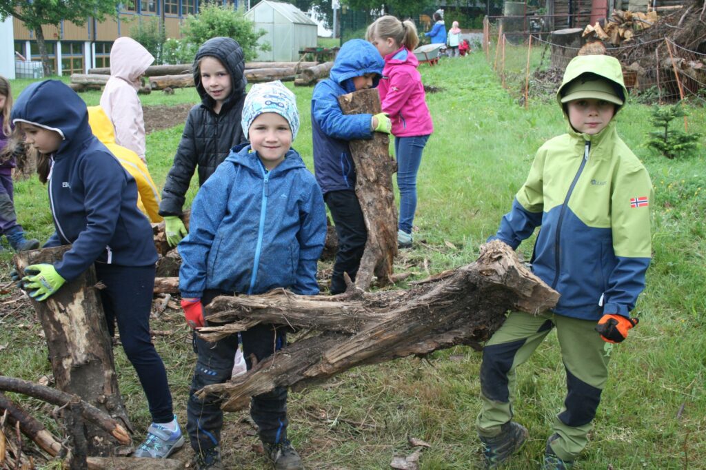 Zwei Kinder schleppen große Äste für die Pyramide heran
