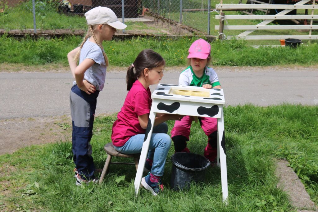 Am Modell üben drei Kinder das Melken