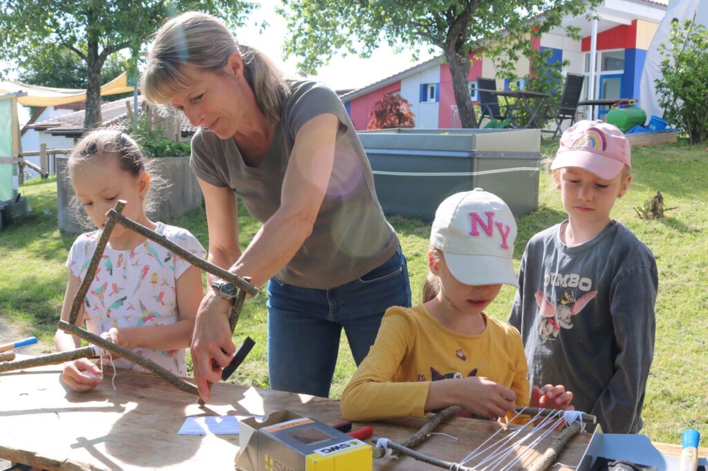 Frau Wiedmann stellt mit den Kindern Naturwebrahmen her