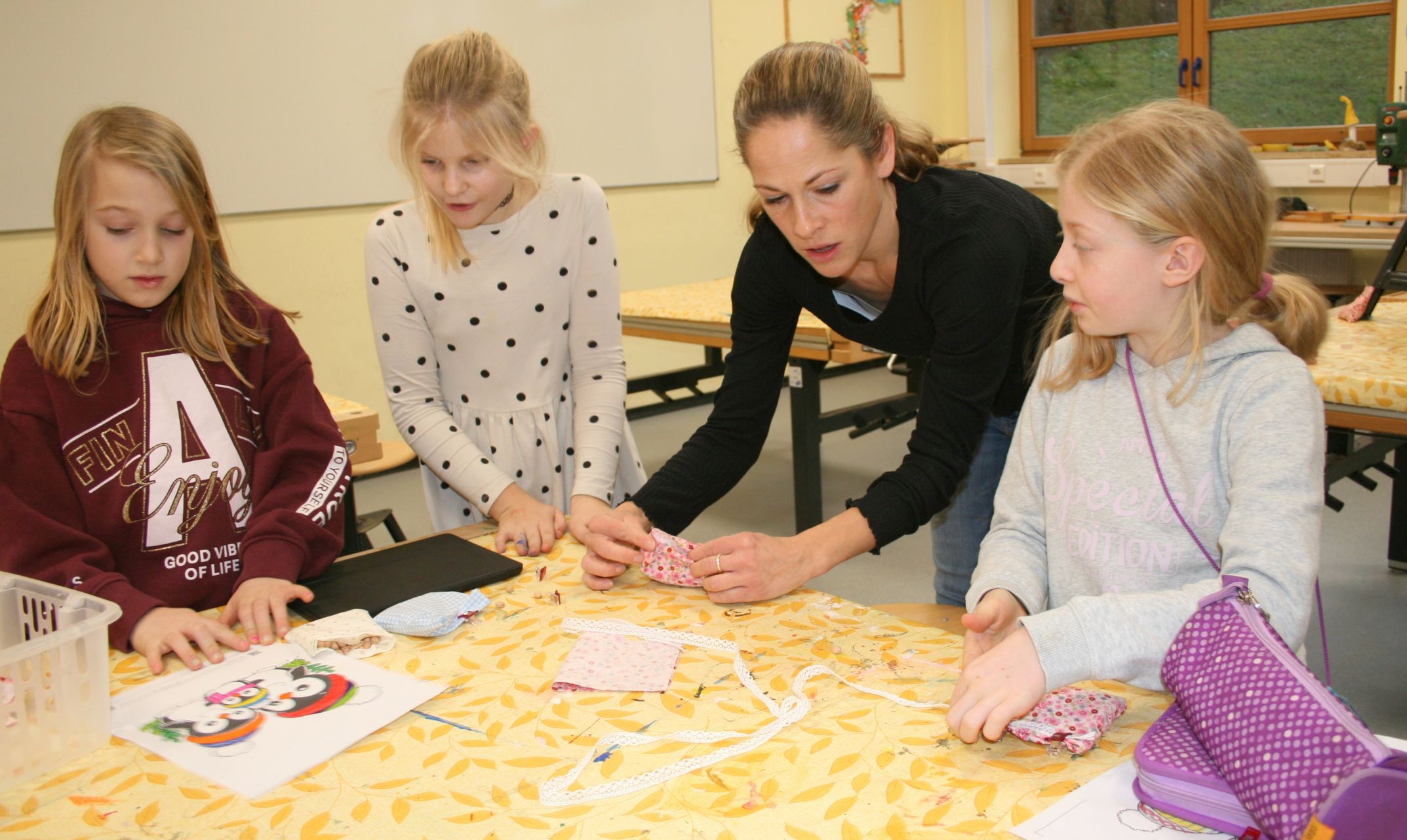 3 Kinder basteln mit der AG-Leiterin am Tisch im Werkraum