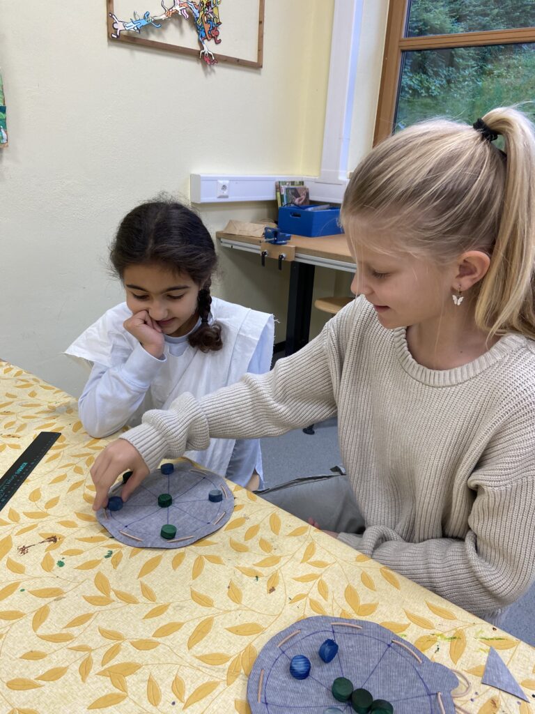 Zwei Mädchen beim Rundmühlespiel aus einem Lederbeutel