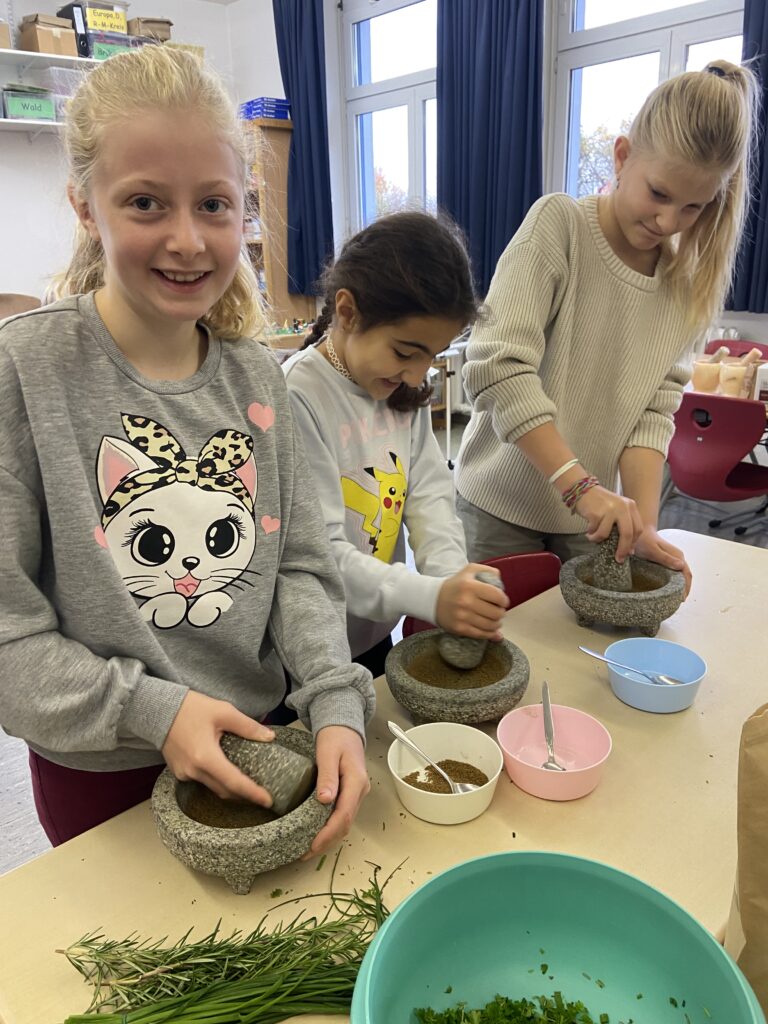Drei Mädchen am Mörser bei der Zubereitung von römischem Essen