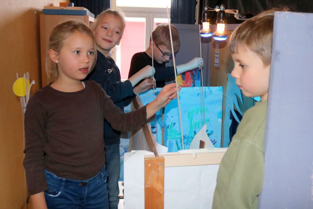 Hinter dem Vorhang stehen die Kinder mit den Stabfiguren.