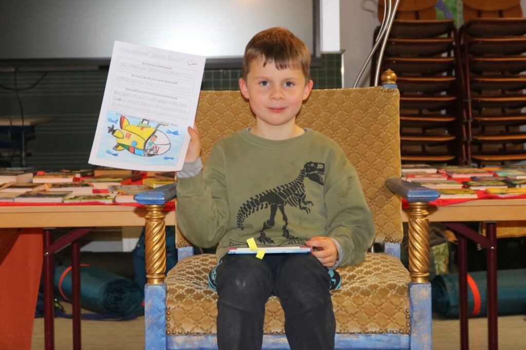 Ein Junge sitzt auf dem Lesethron und stellt sein Buch vor.