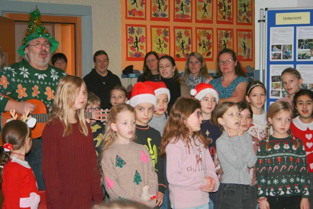 Schüler und Eltern in der Aula beim Singen.
