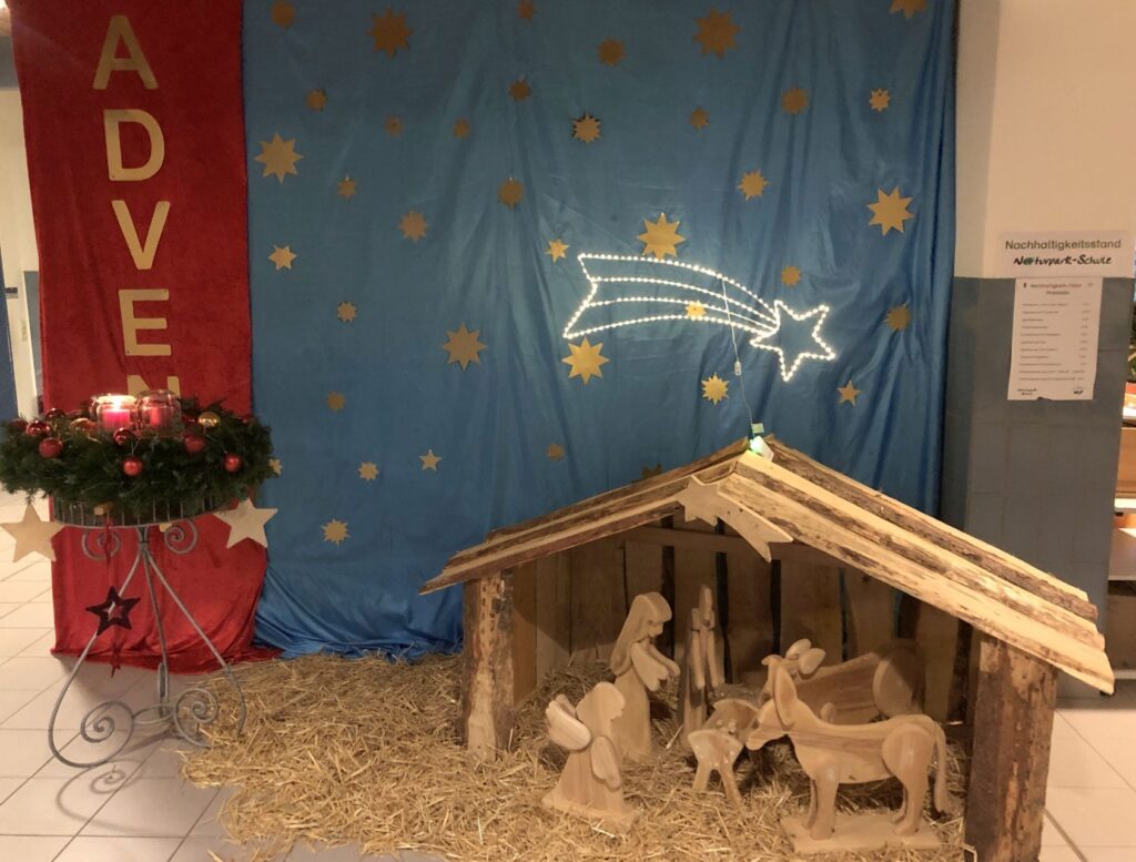Unsere schöne Aula-Dekoration mit Krippe, beleuchtetem Stern und vielen Sternen im Hintergrund.
