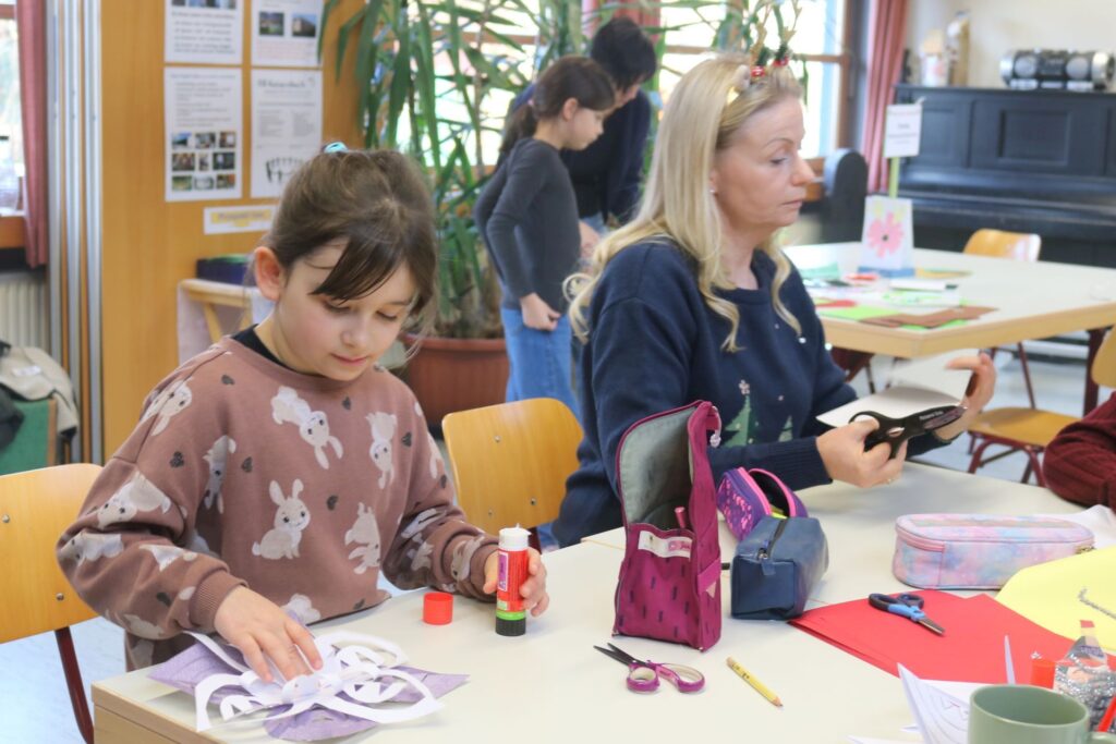EIn Mädchen bastelt gerade einen Weihnachtsstern aus Papier und Pfeifenputzern.