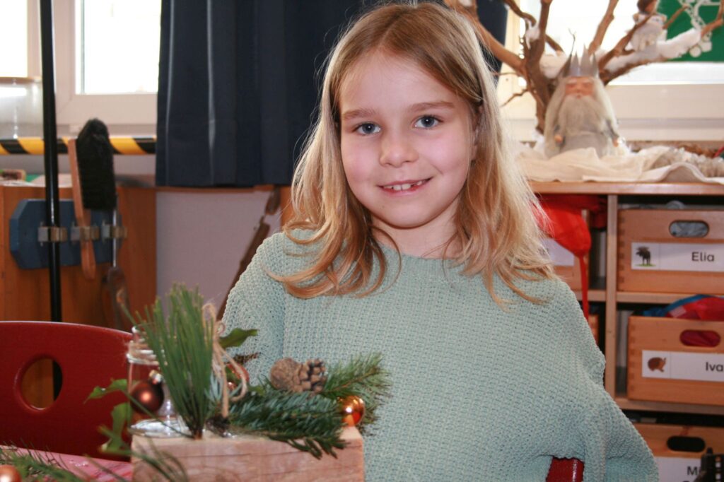EIn Mädchen zeigt stolz ihr tolles Weihnachtsgesteck.