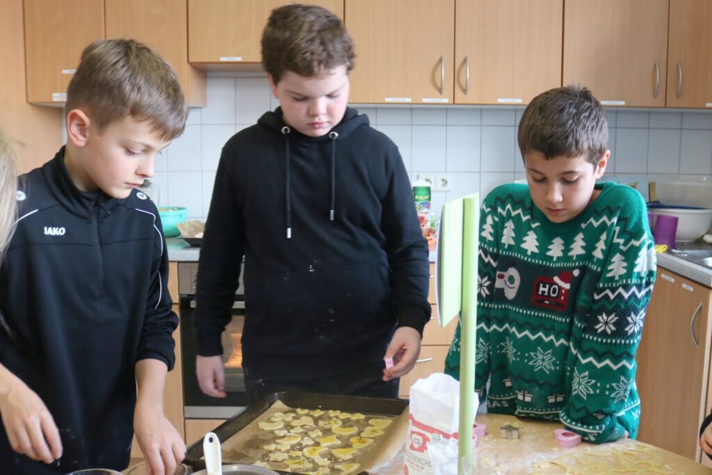 Auch drei Jungs stechen Teig aus und verzieren ihre Plätzchen.