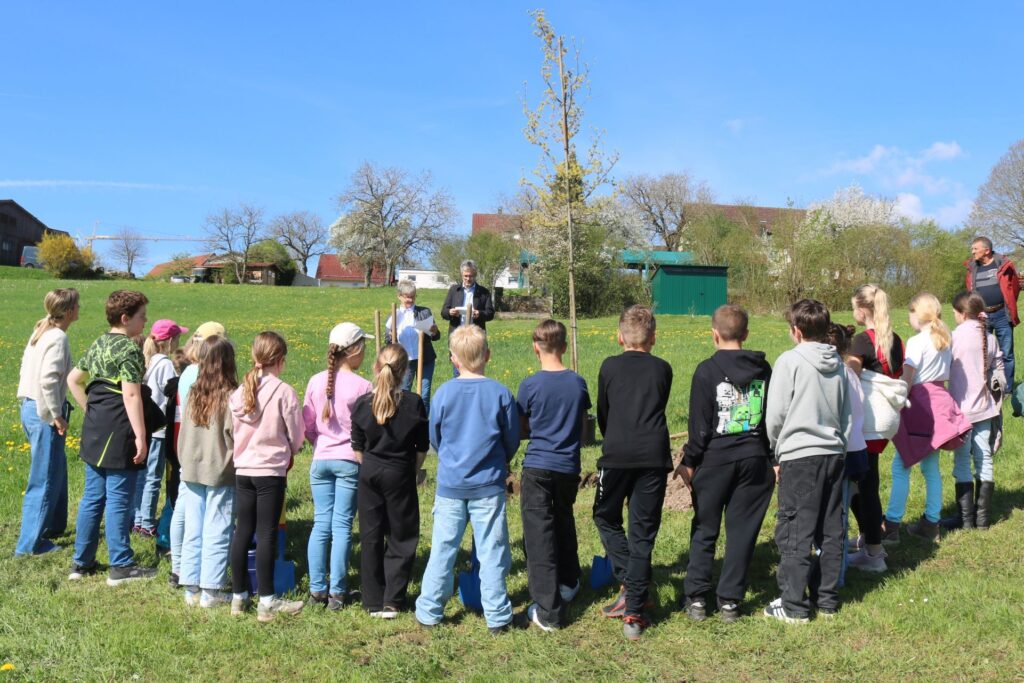 Kinder der Klasse 4 im Halbkreis von hinten hören Bürgermeister Clauss zu.