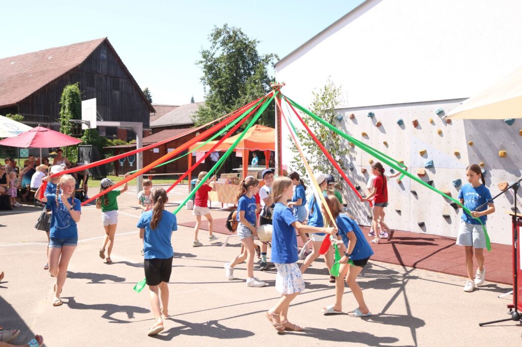 Die Kinder der Musik- Tanz- Theater- AG bei einem traditionellen Bändertanz.