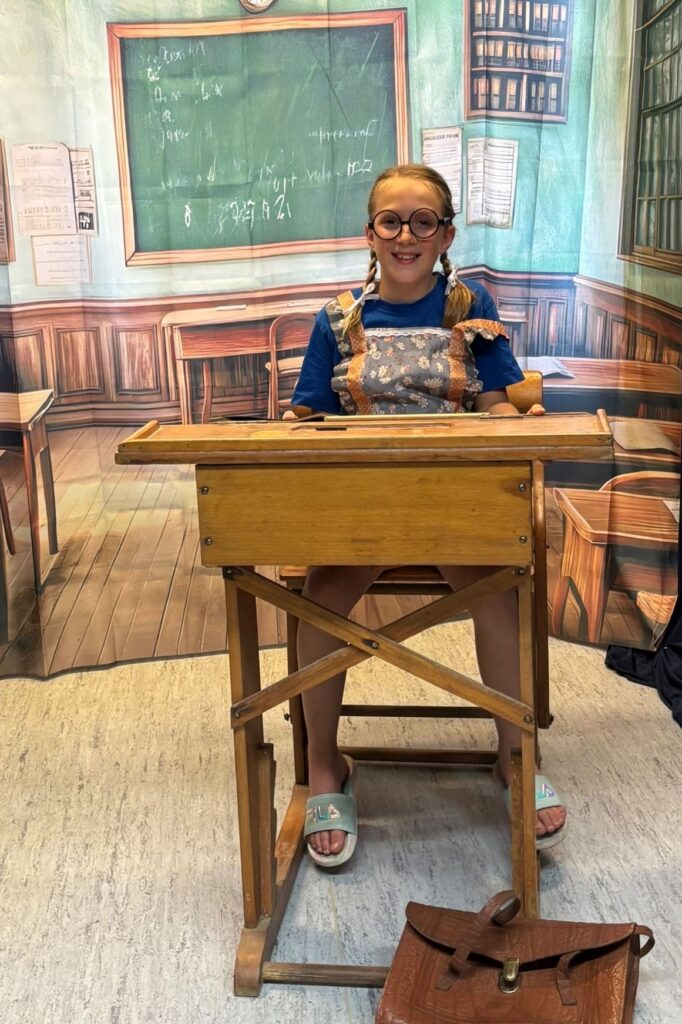 Mädchen in Schulkleidung von damals in der Klassenzimmerkulisse von früher