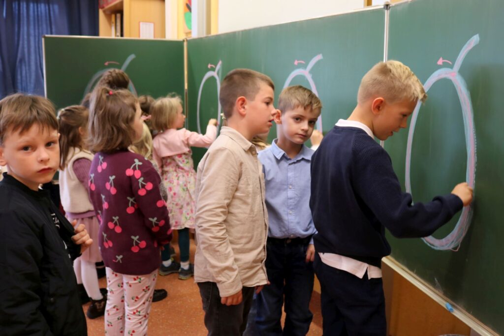 Die Erstklässler spuren an der Tafel das O nach